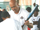 Cal Ripken hands a South African Youth a baseball bat during a training session