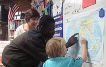 Photo of a teenager pointing at a map with a young child.