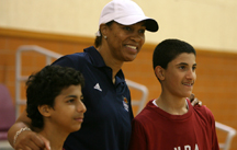 Photo of Carla McGhee embracing two Qatari players after the clinic