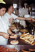 Men working at a counter, preparing wieners