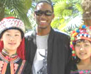 Photo of Gilman alumnus Monty McGee (in the center) with women in traditional dress representing two minority cultures in China