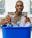 A man putting plastic water bottles in a recycling bin.
