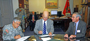 a photo of agroup of men signing papers at a conference table.