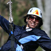 Photo of Faiza finishing the zip line element of a ropes course.