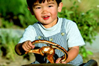 Photograph of a young boy riding a toy car.