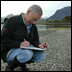 Spill responder on beach making notes.