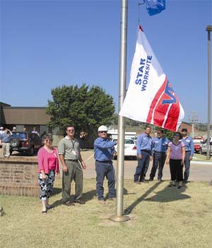Clean Harbors employees (from right to left) Jody Reinhart, Jay Adair, Walter Syms, Jon Mitchell, Alan King, Lee Ann Meek, and Gary Mitchell raise Clean Harbors' first Star VPP flag at their Lone Mountain, Oklahoma Facility in June 2005