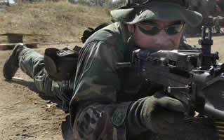 A U.S. Navy SEAL takes aim with an M-60 machine gun during live fire training. 