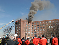Firefighters watch as a fan, simulating wind, changes airflow and smoke conditions during experiments in a seven-story high-rise abandoned apartment building on New York City's Governors Island. The NIST tests examined firefighting techniques such as the use of positive pressure ventilation fans, wind control devices and hose streams to control or suppress heat and smoke from wind driven fires.