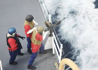 PACIFIC OCEAN – Seaman Blake Tilton fires a an M-240 light machine gun with the assistance of Petty Officer 2nd Class Ezilda Bautista under the supervision of Chief Petty Officer Robert Fenner, a gunner’s mate, during a gunnery exercise onboard the Coast Guard Cutter Bertholf June 19, 2009. Bertholf’s crewmembers routinely train on all weapon systems to ensure competency and maintain qualifications. (U.S. Coast Guard photo/Petty Officer 3rd Class Michael Anderson) 