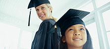 A girl and young woman, both wearing graduation cap and gowns