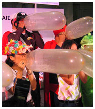 Mechai Viravaidya speaks while event attendees blow condom balloons