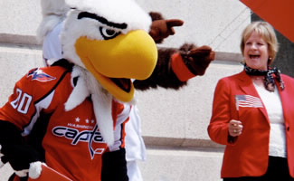 oto of Helen Marano (right), Director, Office of Travel and Tourism Industries, with Washington Capitals mascot "Slapshot" on the steps of the National Portrait Gallery while participating in U.S. Travel Rally Day. (U.S. Department of Commerce photograph)