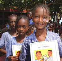 photo, young students in Guinea proudly hold new textbooks