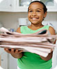 A girl holding a stack of newspapers.