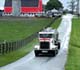 Truck coming down a country road with a barn in the background