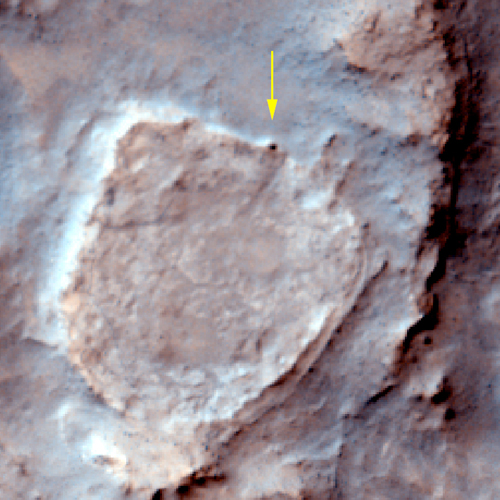 This false-color image shows the view looking down from orbit at the area where Spirit has spent the past Martian winter. Spirit is visible as a black dot on the northeast face of the plateau. To the west (left) are a low peak, a round plateau, and a series of east-west trending ripples. To the south is a low ridge, an elongated plateau, a small crater, and a small peak. To the east (right) is another low ridge and beyond it, a rugged, rocky surface.