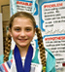 Photo: young girl in pigtails, before her science project display board.