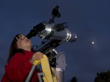 Girl viewing the moon through a telescope.