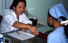 Photo of a factory clinician providing medication for a young garment worker.