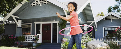 Photo: A girl playing with a hoola hoop in front of her home.