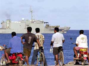 Local men watch as an Australian navy ship passes near the Nauru coast, September 18, 2001. [© AP Images]