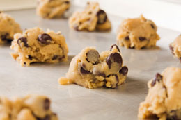 Chocolate-chip cookie dough laid out on a silver baking tray.
