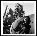 Esther Bubley, Farm Security Administration/Office of War Information photographer, three-quarter length portrait, kneeling with camera, facing right, at Bayway, New Jersey. LC-USZ62-121073