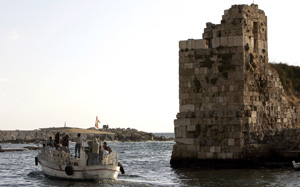 Tourists in a boat ride past an ancient fortress at the port city of Byblos (Jbail), Lebanon, August 21, 2006. [© AP Images]