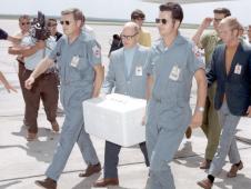 Dr. Howard Schneider and Gary McCollum are carrying the e Apollo 11 Lunar Sample Return Container with the moon rocks for quarantine.