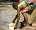 Photo of boy scooping water from a river