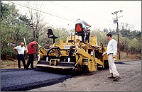 Photo of paving equipment as new road is laid in rural setting.