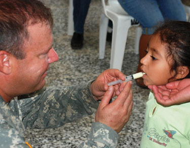 Captain Andy Dula administers medicine to a little girl during a military-medical exercise held at the Brazos de Amor Community Center in Poptún Guatemala.