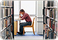 Person seated, surrounded by books