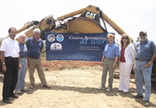 Workers and Lubchenco pose in front of earthmoving equipment. Click for larger image.