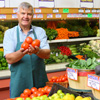 Store owner holding fresh vegetables