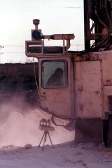 Cab of large construction machine enveloped in dust