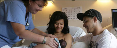 Foto: una profesional de la salud entregándole el recién nacido a una pareja jóven