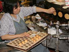 Photo: a woman making fortune cookies at a factory.