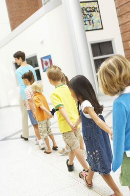 Elementary school-aged children in a line, heading into school.