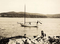 View of women on a sailboat, and two women on shore.