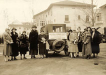 A group of women around an automobile.