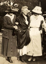 A weakened woman is assisted while walking by two other women.