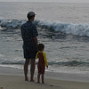 photo a a man and boy standing on the beach, looking out at the waves