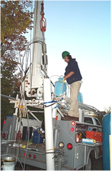 USGS technician lowering the BAT3 into a standpipe to decontaminate it before moving on to another well at the University of Connecticut Landfill Study Area, Storrs, CT