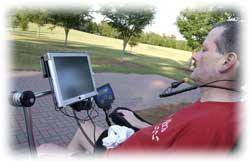A man using assistive technology to direct his wheelchair outdoors