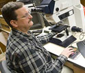 Photo of Peter Siver using a light microscope and a computer to study diatoms