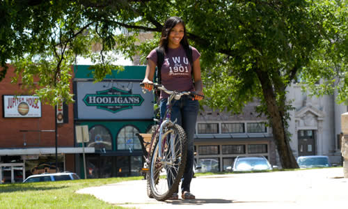 photo of TWU student with her bicycle on the Denton Square