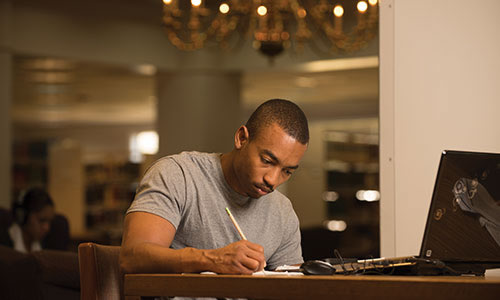 photo of a male student at TWU studying in the library