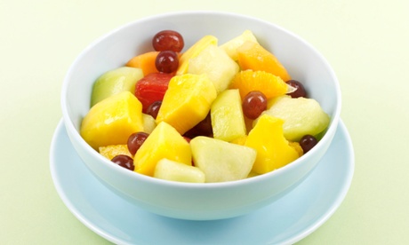 White bowl containing mixed fruit salad: grapes, pineapple, orange, grapefruit and more.